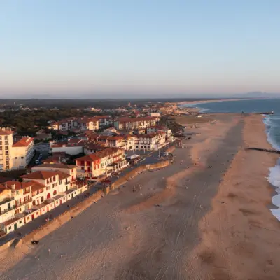 Coucher de soleil sur la Plage centrale d’Hossegor, vue depuis la place des Landais, avec l’océan Atlantique illuminé par des teintes dorées et orangées.